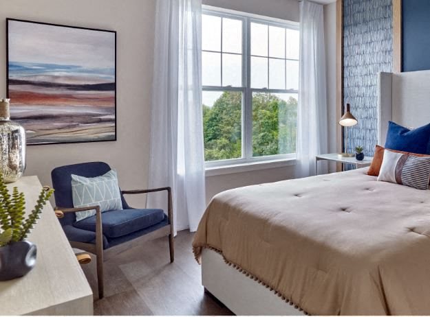 a bedroom with a large bed and a chair in front of a window